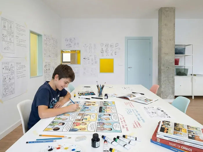 Niño dibujando su cómic, con los de la clase expuestos en la pared